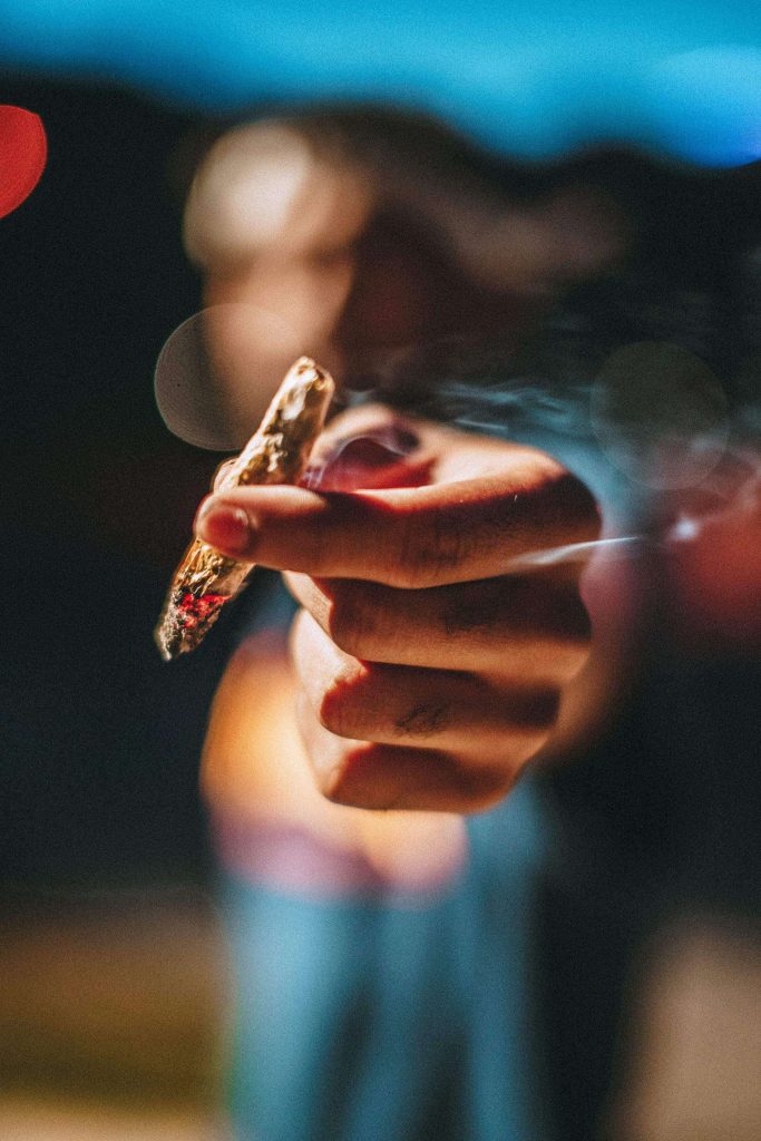 man passing a rolled marijuana joint